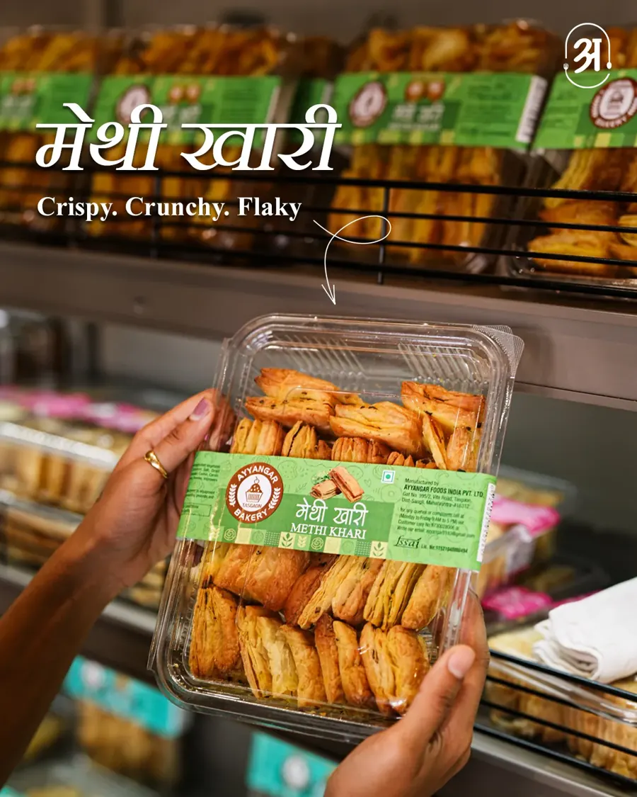 Hand holding a pack of methi khari at a snack counter