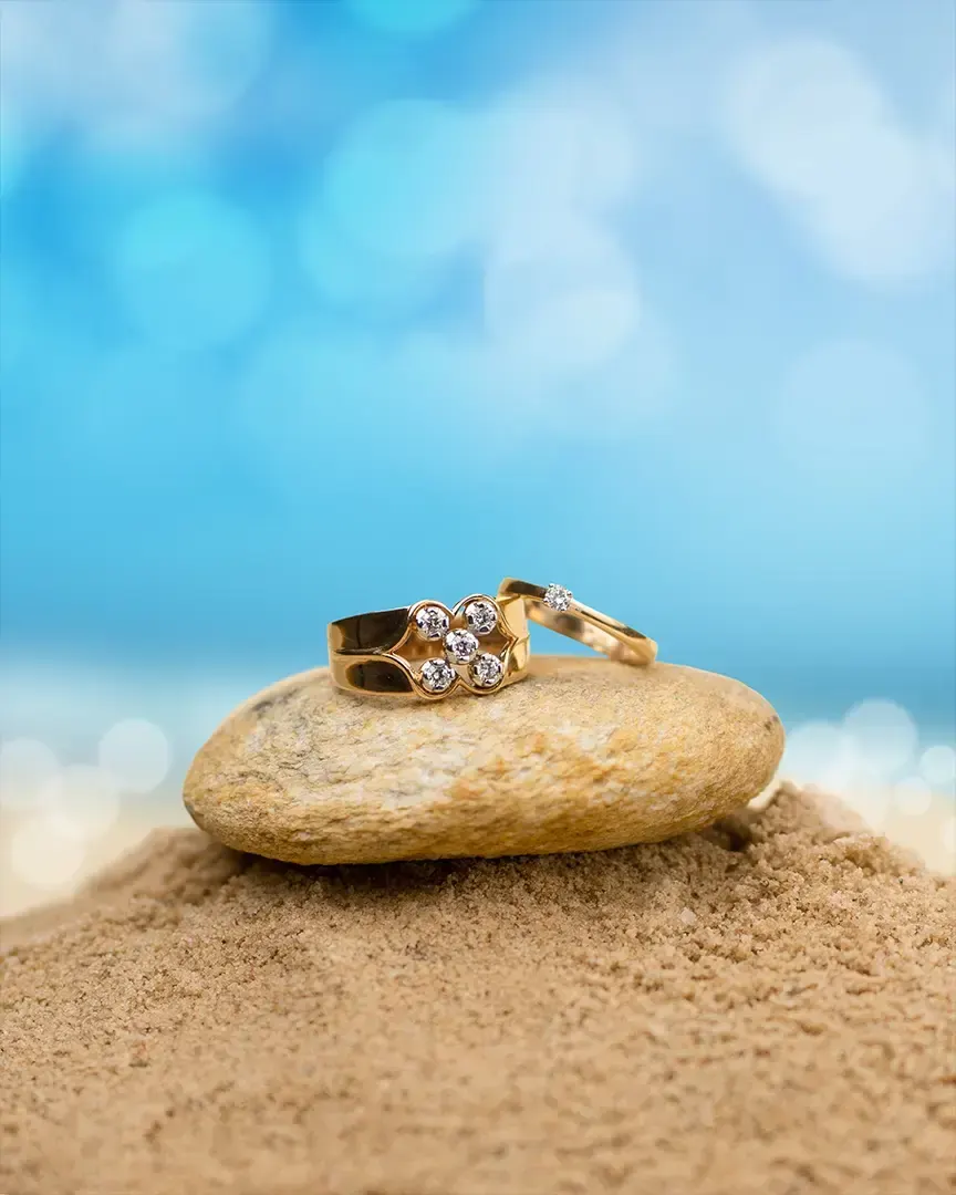 Gold ring resting on a pebble on a beach