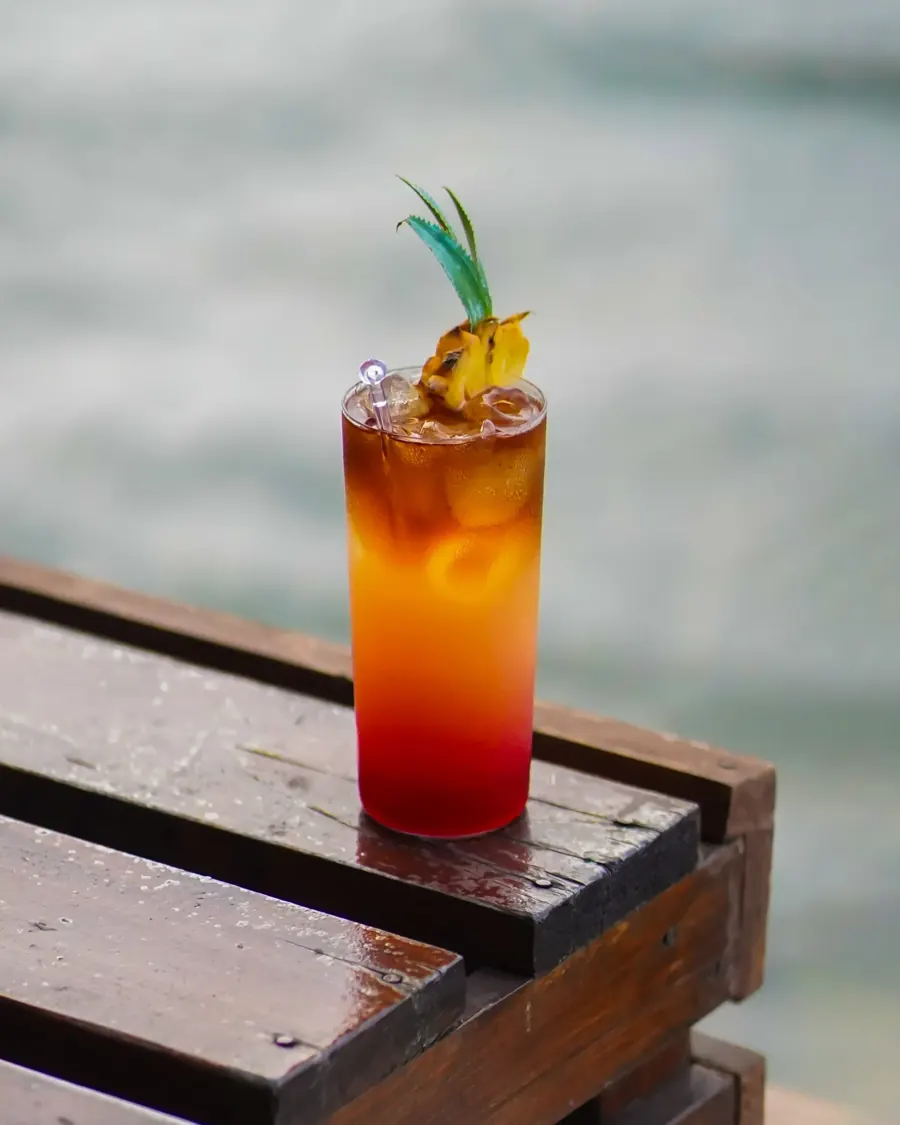 Orange cocktail on a wooden railing by the lake